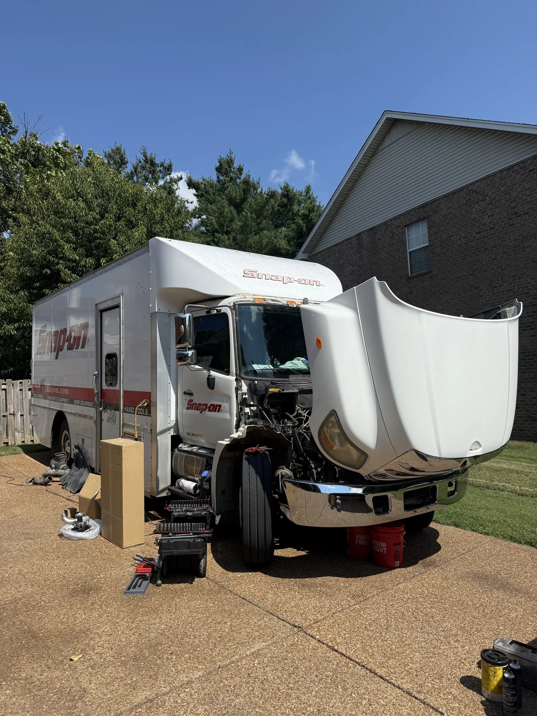 Heavy-duty truck parked at a service site with the tool drawers open