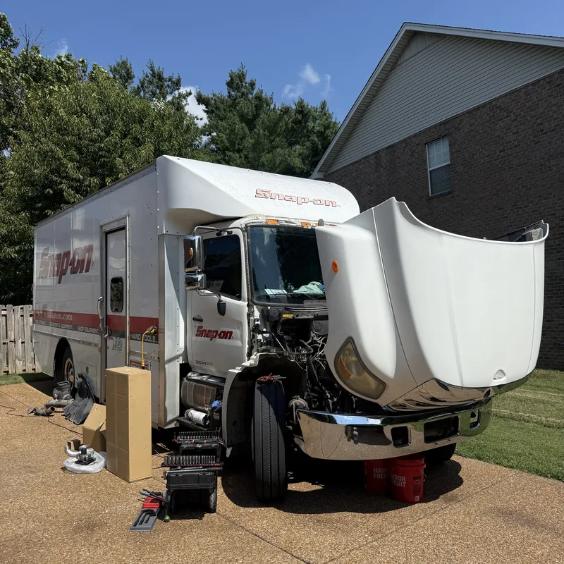 Heavy-duty truck parked at a service site with the tool drawers open