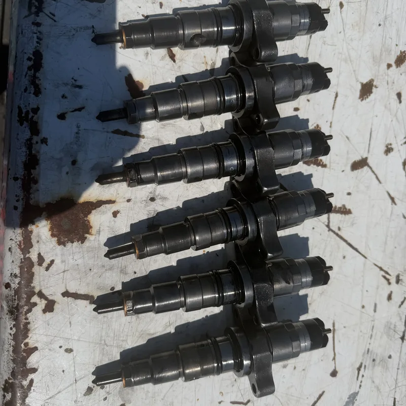 Six diesel fuel injectors lined up on a workbench