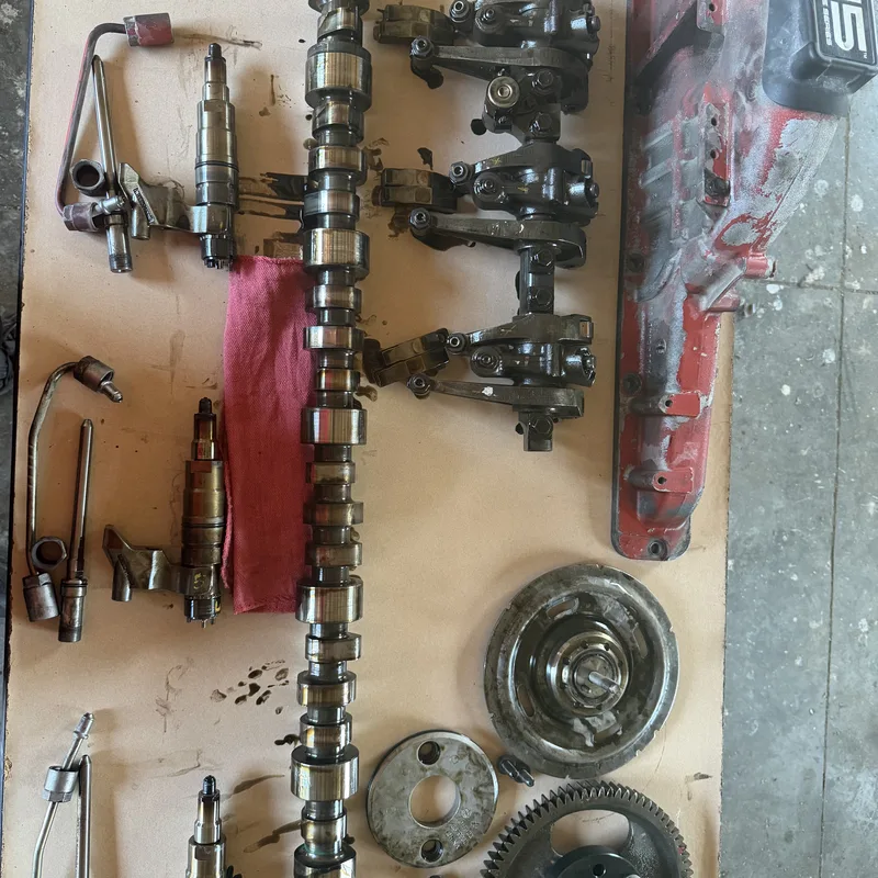 Heavy-duty diesel valve-train components laid out — camshaft, rocker assemblies, gears, injectors
